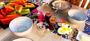 una mesa con platos y tazones de fruta. en Chambres d'hôtes Les Cases BéNaDou en Ngaparou