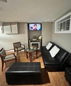 a living room with a black leather couch and a tv at West Edmonton Perle Palace in Edmonton