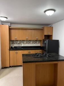 cocina con armarios de madera y encimera negra en Apartamento 301 Calle Principal, en Guatapé