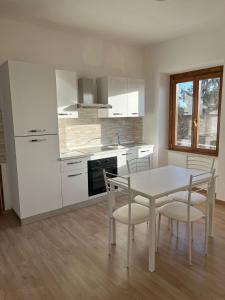 Una cocina con gabinetes blancos y una mesa y sillas. en Moderni Appartamenti Appia Terracina, en Terracina