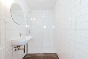 a white tiled bathroom with a sink and a mirror at Surf & Sea Suites in Parede
