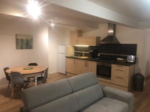 ein Wohnzimmer mit einem Sofa und einem Tisch sowie eine Küche in der Unterkunft Logement entier sur Wormhout in Wormhout