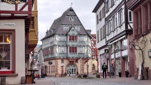 un vecchio edificio con torretta su una strada cittadina di Hotel zum Riesen - älteste Fürstenherberge Deutschlands a Miltenberg