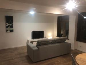 ein Wohnzimmer mit einem Sofa und einem Flachbild-TV in der Unterkunft Logement entier sur Wormhout in Wormhout