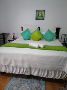 a large bed with green and white pillows on it at Ezamampondo Guest House in King Williamʼs Town
