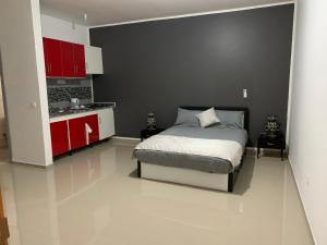 a bedroom with a bed and a kitchen with red cabinets at J Martins Apart Hotel in Tarrafal