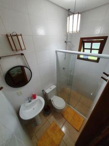 y baño con aseo, lavabo y espejo. en Hospedaria Morada das Orquídeas en São Sebastião