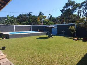 a backyard with a swimming pool and an umbrella at Hospedaria Morada das Orquídeas in São Sebastião