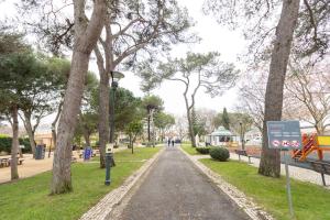 a walkway in a park with trees and a sign at Surf & Sea Suites in Parede