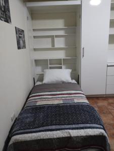 a bed in a room with white shelves at Habitación - Estudio in San Lucas Sacatepéquez