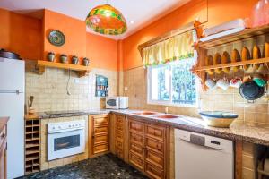 cocina con paredes de color naranja y nevera blanca en La Veguilla Úbeda, en Úbeda
