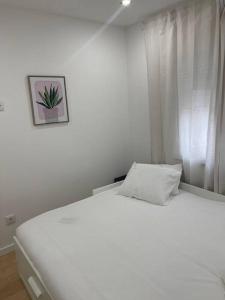 a white bed in a bedroom with a picture on the wall at Lovely 2 bedroom apartment in South Lisbon in Barreiro +6 photos