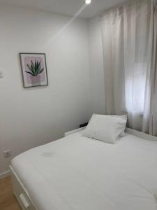 a white bed in a bedroom with a picture on the wall at Lovely 2 bedroom apartment in South Lisbon in Barreiro