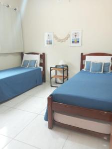 a bedroom with two beds and a table in it at CASA DOS BONS VENTOS - À 6 minutos da praia de carro in Itaipuaçu