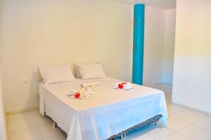 a bed with a white table with flowers on it at Caminho do Paraíso in Porto De Galinhas