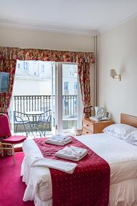 um quarto de hotel com uma cama com um cobertor vermelho em Afton Hotel em Eastbourne