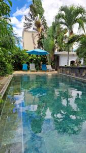 - une piscine avec 2 chaises et un parasol bleu dans l'établissement Luxury Villa L'ile Maurice, à Pointe aux Cannoniers