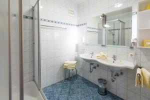 a white bathroom with a sink and a mirror at Hotel Pension Appartement Kristall in Tröpolach