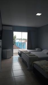 a bedroom with two beds and a window with a view at Hotel Caçula São Gabriel in São Gabriel