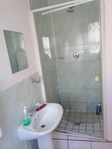 a white bathroom with a shower and a sink at Ezamampondo Guest House in King Williamʼs Town