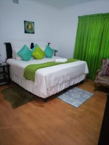a bedroom with a large bed with green curtains at Ezamampondo Guest House in King Williamʼs Town