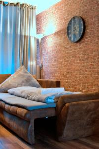 a couch sitting next to a brick wall with a clock at Industrial Style 77qm mit Balkon in Herne