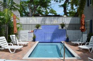 a swimming pool with two lawn chairs at Nassau Suite Key West in Key West