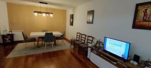 uma sala de estar com uma mesa e cadeiras e uma televisão em Private Bathroom Room Shared Kitchen no Porto