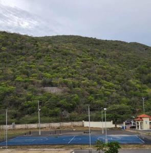 a tennis court in front of a mountain at Condo with pool in Portmore in Portmore