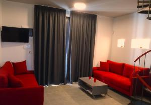a living room with a red couch and a tv at Aurora Suites in Nea Fokea