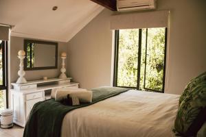 1 dormitorio con 1 cama con espejo y ventanas en Idube Guest House, en Winterton