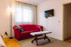 un soggiorno con divano rosso e tavolo di Apartment Jasna a Belgrado