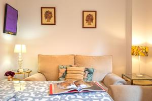 a bedroom with a couch and a book on a bed at Apartamento con Piscina - La Palmera in Seville