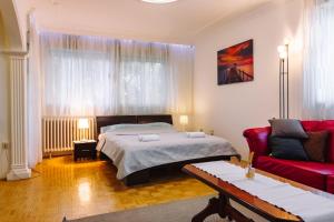 una camera con un letto e un divano rosso di Apartment Jasna a Belgrado