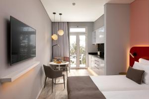 a bedroom with a bed and a table and a kitchen at King David Suites by Madeira Sun Travel in Funchal