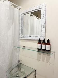 two bottles of wine sitting on a glass shelf next to a sink at Mono Ambiente en Palermo Hollywood in Buenos Aires
