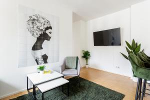 a living room with a chair and a tv at Global Living - Design Apartment I Central I Smart-TV I Kitchen I Berlin in Berlin