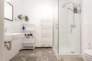 baño blanco con ducha y lavamanos en Global Living - Design Apartment I Central I Smart-TV I Kitchen I Berlin en Berlín