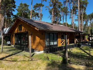 een blokhut in het bos met een hek bij Domek Dębowy 1 in Lubniewice