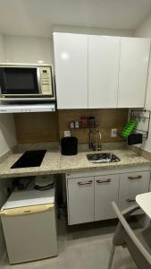 a kitchen with white cabinets and a microwave at Studio Reformado coração Leblon in Rio de Janeiro