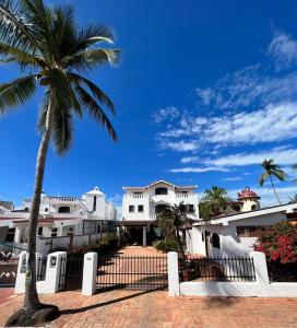 una palmera frente a una casa blanca en Beachfront Villa en Rincón de Guayabitos