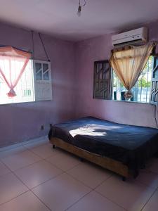 a bedroom with a bed and two windows at Casa na ilha de Itaparica in Itaparica
