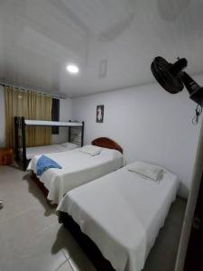 2 camas en una habitación con paredes blancas en Cómoda casa de campo en Ibagué