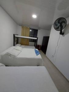 een slaapkamer met 2 bedden en een ventilator aan de muur bij Cómoda casa de campo in Ibagué