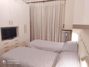 1 Schlafzimmer mit 2 Betten, einem TV und Vorhängen in der Unterkunft Gioiello a Torino in Turin