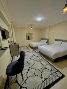 1 dormitorio con 2 camas, silla y TV en Glamour Pyramids Hotel en El Cairo