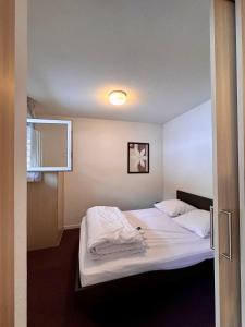 - une chambre avec un grand lit et des draps blancs dans l'établissement Aux pieds des pistes, à La Foux