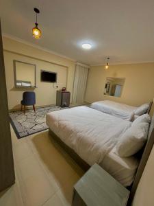 une chambre d'hôtel avec deux lits et une chaise dans l'établissement Glamour Pyramids Hotel, au Caire