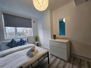 a bedroom with a bed with a window and a dresser at London Mile End Rooms in London