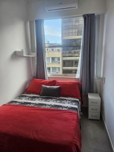 1 dormitorio con cama roja frente a una ventana en Studio Reformado coração Leblon, en Río de Janeiro